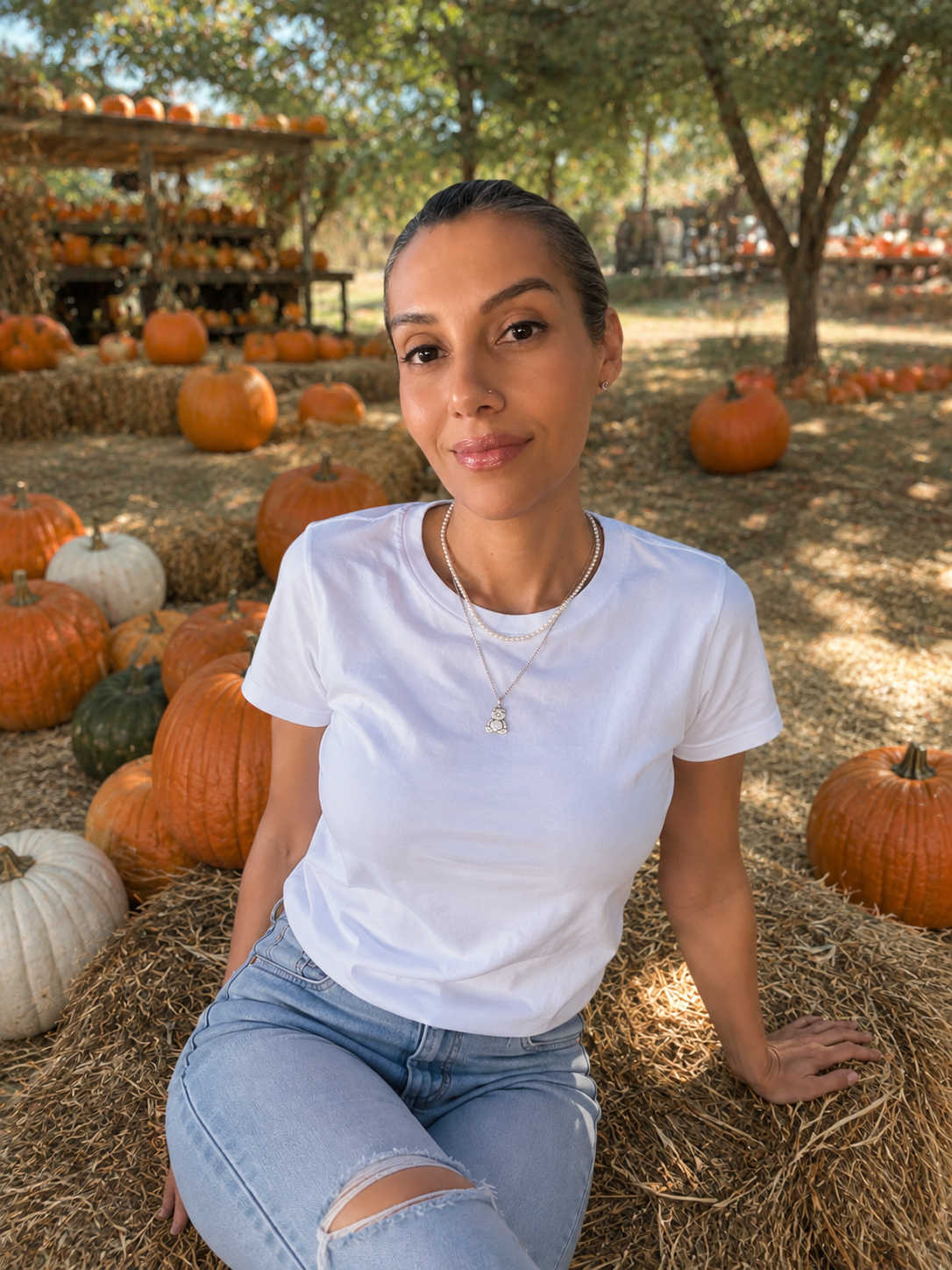 Erika, founder of Porch in Seasons, seated outdoors among pumpkins and hay bales